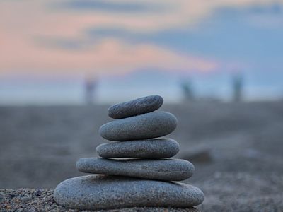 Stacked stones on a beach with a calm sea in the background.